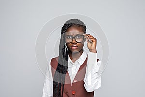 Portrait of happy young african business woman wearing glasses standing looking camera over grey background