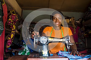 Portrait of a happy young african female tailor smiling while working with her sewing machine