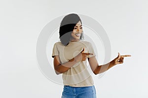 Portrait of happy young african woman pointing at side with both hands on white background