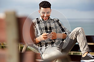 Happy young arabic man sending text message on mobile phone