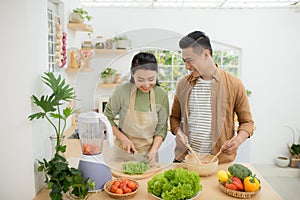 Portrait of happy young Asian couple cooking together in the kitchen at home