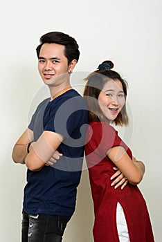 Portrait of happy young Asian couple leaning on each other with arms crossed