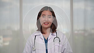 Portrait of happy young Asian female doctor talking to patient via video call