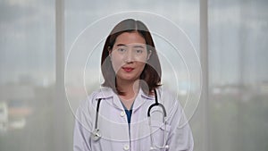 Portrait of happy young Asian female doctor talking to patient via video call