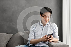 Portrait of a happy young asian man using mobile phone