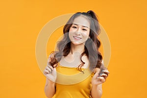 Portrait happy young asian woman feeling carefree laughing positive emotion on yellow background