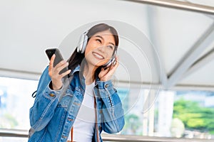 Portrait of happy young asian woman listening music online with wireless headphones