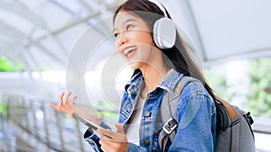 Portrait of happy young asian woman listening music online with wireless headphones