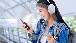 Portrait of happy young asian woman listening music online with wireless headphones