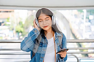 Portrait of happy young asian woman listening music online with wireless headphones