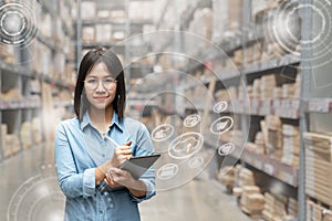 Portrait of happy young attractive asian entrepreneur woman looking at camera using smart tablet in warehouse with inventory