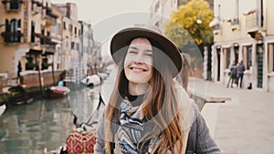 Portrait of happy young attractive woman smiling, taking a photo with professional camera by famous Venice canal, Italy.