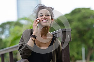 Portrait of happy young beautiful African woman talking on the phone at the park