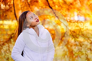 Portrait of a happy young beautiful woman in autumn season in white woolen jacket outdoor with colorful autumn background.
