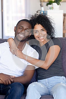 Portrait of happy young black couple posing hugging at couch