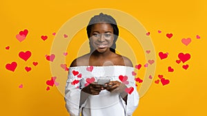 Portrait Of Happy Young Black Woman Holding Smartphone, Yellow Background