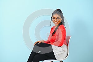 Portrait of happy young black woman laughing against blue wall.