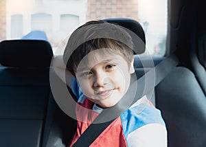 Portrait Happy Young boy siting in safety car seat looking at camera with smiling face,Child sitting in the back passenger seat