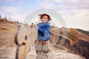 Portrait of happy young boy sitting on a wooden bench outdoors