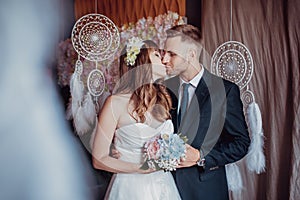 Portrait of happy young bride and groom in a classic interior near the dream catchers. Wedding day, love theme. First day of a new