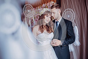 Portrait of happy young bride and groom in a classic interior near the dream catchers. Wedding day, love theme. First day of a new