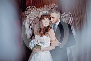 Portrait of happy young bride and groom in a classic interior near the dream catchers. Wedding day, love theme. First day of a new