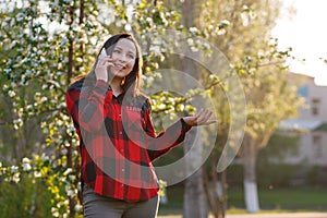 Portrait of a happy young brunette girl with a smartphone in her hand, raised to her ear. Girl talking on mobile and smiling. shot