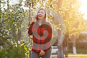 Portrait of a happy young brunette girl with a smartphone in her hand, raised to her ear. Girl talking on mobile and smiling. shot