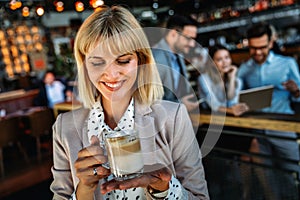 Portrait of happy young business woman drinking coffee in a break. In the background, her colleagues