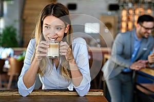 Portrait of happy young business woman drinking coffee in a break. In the background, her colleagues