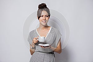 Portrait of a happy young business woman holding cup of coffee isolated over white background.