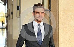 Portrait of happy young businessman standing in hotel lobby.