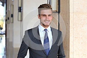 Portrait of happy young businessman standing in hotel lobby.