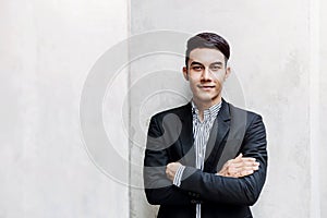 Portrait of Happy Young Businessman standing at the Wall, Smiling and Crossed Arms, Looking at camera