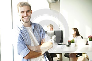 Portrait of a happy young casual businessman at office, smiling.