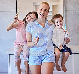 Portrait of happy young caucasian family holding toothbrushes and smiling showing off their healthy teeth. Young mother