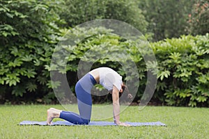 Portrait of happy young caucasian woman exercising yoga outdoors early morning. Beautiful girl practicing asana on blue