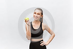 Portrait of a happy young caucasian woman holding and eating green apple over white background