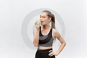 Portrait of a happy young caucasian woman holding and eating green apple over white background