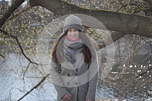 Portrait of happy young Caucasian woman in warm clothes smiling at camera. Cheerful beautiful brunette girl posing