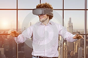 Portrait of happy young cheerful excited man with curly hair wearing vr headset.
