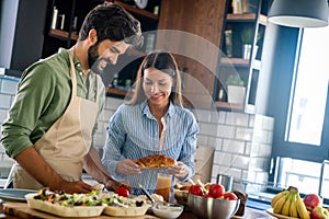 Portrait of happy young couple cooking together in the kitchen at home.