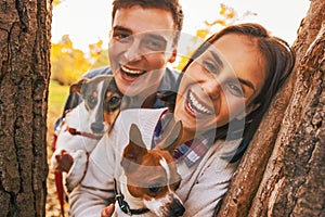 Portrait of happy young couple with dogs outdoors in autumn park