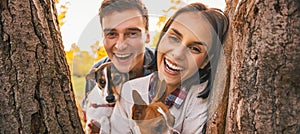 Portrait of happy young couple with dogs outdoors in autumn park