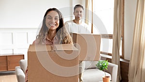 Portrait happy young couple holding boxes, moving into new house