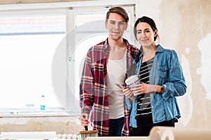 Portrait of a happy young couple holding tools for home remodeling