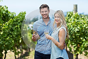Portrait of happy young couple holding wine bottle and glass