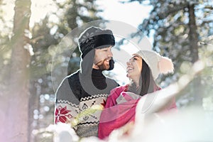 Portrait of happy young couple looking at each other and smiling in winter forest