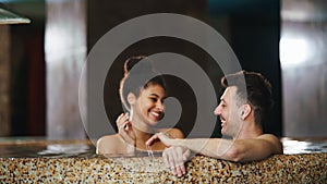 Portrait of happy young couple in love in swimming pool, having fun.