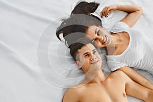 Portrait of happy young couple lying on bed together